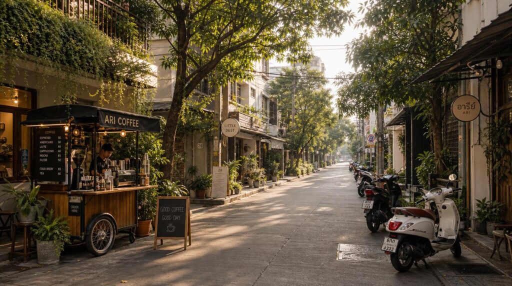 A quiet tree-lined Ari side street in soft morning light, a local coffee cart and a few parked scooters, low-rise buildings