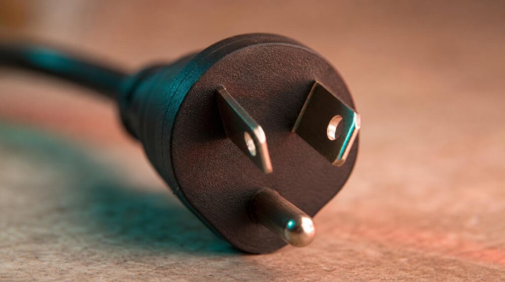 Close-up macro shot of a Type I plug's two flat pins angled into a V with a third grounding pin below